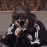 a girl in a black and white striped jacket is holding a sniper rifle ..