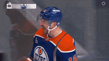 a hockey player wearing number 18 stands in front of a goal screen