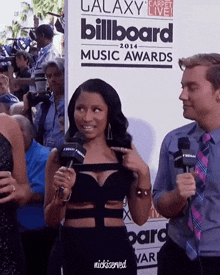 a woman is standing in front of a billboard that says music awards