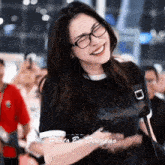 a woman wearing glasses and a black shirt is smiling .