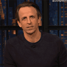 a man wearing a black sweater has the hashtag latenightseth on the bottom right
