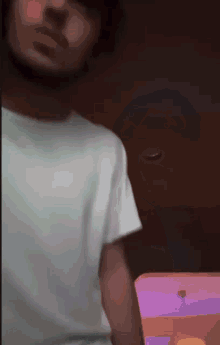 a man in a white shirt is holding a pink and purple object