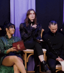 a woman in a green jacket sits next to a man and a woman in black