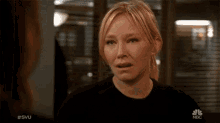 a woman is crying in front of a nbc screen