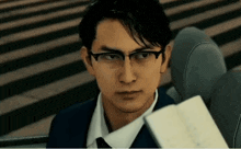 a man wearing glasses and a suit looks at something