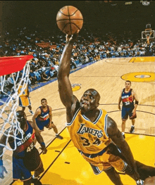 a basketball player wearing a lakers jersey is jumping to dunk the ball