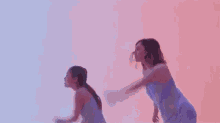 a woman and a little girl are standing next to each other in a pink and blue room .