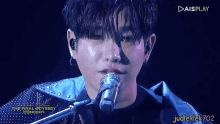 a close up of a person singing into a microphone with aisplay in the corner
