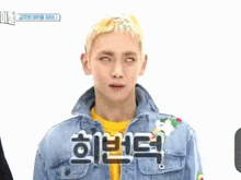 a man wearing a denim jacket and a yellow shirt with chinese writing on his chest