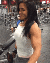 a woman in a white tank top is lifting weights in a gym that says life fitness
