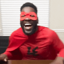 a man is wearing a red cape and a mask with the letter l on his shirt