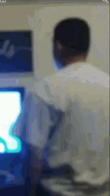 a blurry picture of a man sitting in front of a computer screen