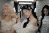 three women are standing next to each other in a room . one of the women is wearing curlers in her hair .