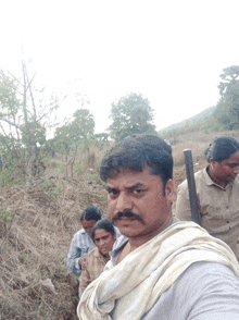 a man with a mustache is standing in a field with a group of people