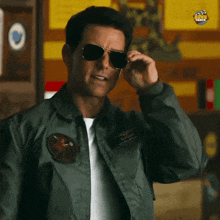 a man adjusts his sunglasses while wearing a green jacket with a patch on it