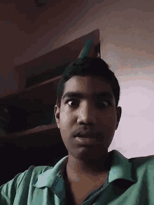 a young man in a green shirt is looking down at the camera