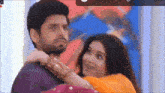 a man is holding a woman in his arms while they are looking at each other .