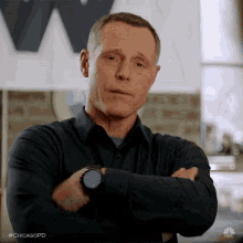 a man is standing with his arms crossed in front of a sign that says chicagopd on it