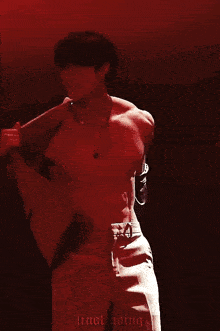 a shirtless man is standing on a red background .