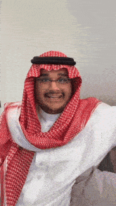 a man wearing glasses and a red and white scarf smiles