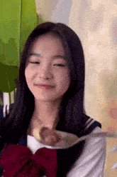 a girl in a school uniform is holding a spoon in her hand