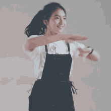 a woman wearing overalls and a white shirt with a flower on it is dancing