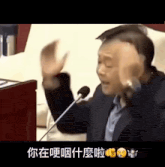 a man in a suit speaking into a microphone with chinese writing on it