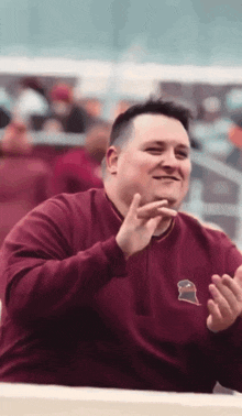 a man wearing a maroon sweatshirt with a gator on it