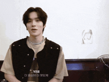 a young man wearing a black vest and a necklace with the word wish on it