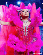 a drag queen in a pink dress with feathers on her head