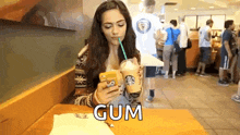 a woman is drinking a starbucks drink through a straw and using her phone .