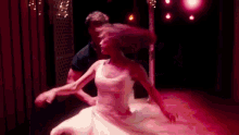 a man and a woman are dancing on a stage in a dark room .