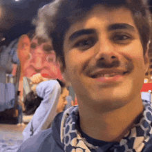 a man with a mustache is smiling and wearing a blue and white shirt