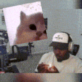 a man wearing headphones is holding a candle and a picture of a cat is above him