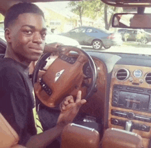 a young man sitting in a bentley car giving a peace sign
