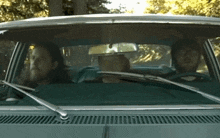two men are sitting in a car with a rear view mirror