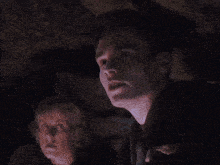 a man with a k on his face is standing in a dark cave
