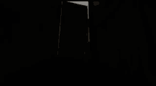 a person is standing in a dark room holding a door open .