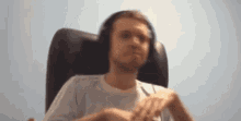 a man is sitting in a chair wearing headphones and making a funny face .