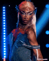 a woman in a blue dress is standing in front of a row of blue lights with t4yce tumblr in the lower right corner