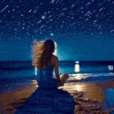 a woman is sitting on the beach at night under a starry sky