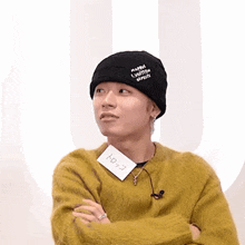 a man wearing a yellow sweater and a black hat has a tag around his neck that says ' tokyo ' on it