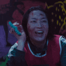 a woman with blood on her face is laughing while holding a toothbrush .