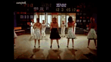 a group of people are dancing in front of a scoreboard that says " zatejmik " on the bottom