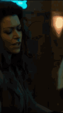 a woman in a dark room is holding a glass in her hand