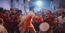 a man in a yellow shirt is dancing in front of a crowd with a x on his back