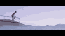 a man is standing on a wooden dock overlooking the ocean .