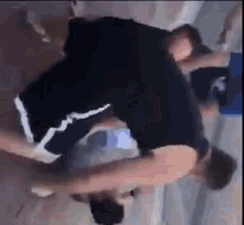 a man in a black tank top and shorts is doing a handstand on a wooden floor .