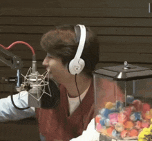a man wearing headphones talks into a microphone in front of a candy machine