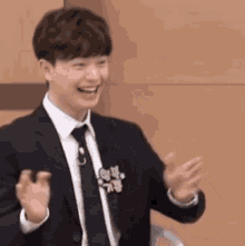 a young man in a suit and tie is clapping his hands .